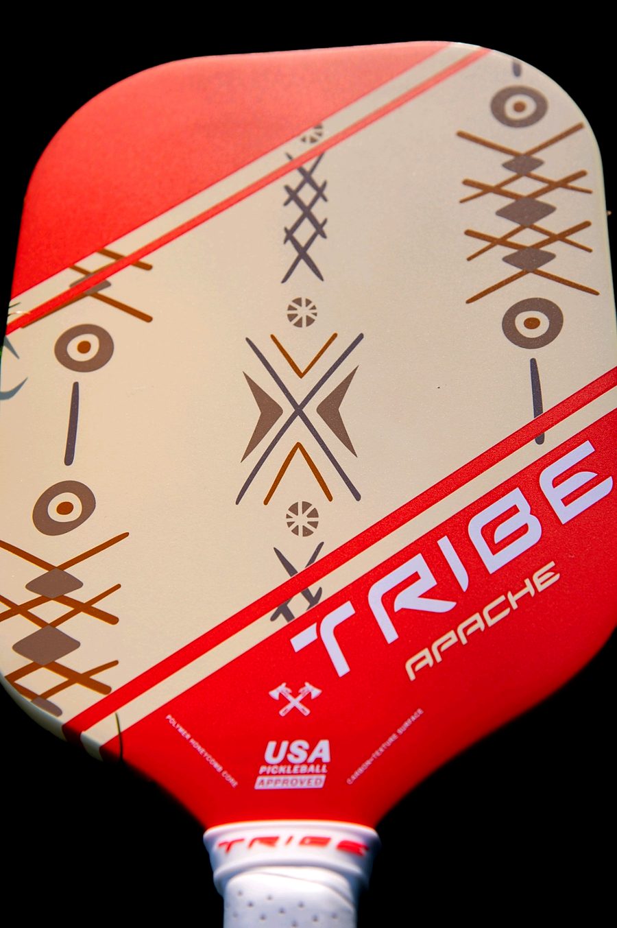 Close detail of the Apache paddle face: crossed arrow forms, concentric circles and hatched line work in ochre and gray on cream